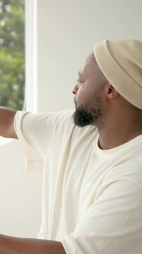 Vertical video: Host tapping tablet making waveform at mic while glancing out window for podcasting