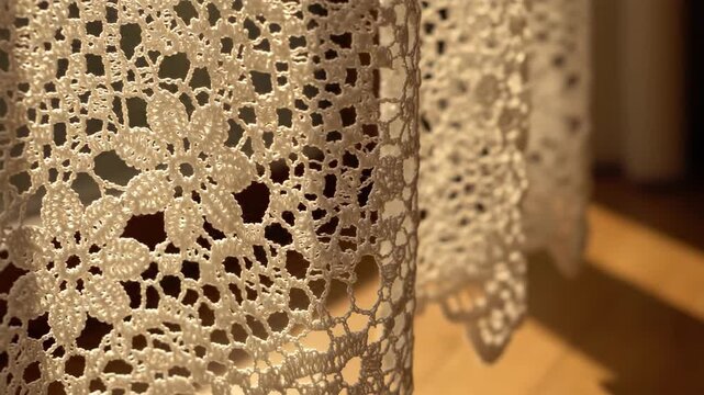 Sunlit lace curtains cast intricate floral shadows on a wooden floor in a warm, serene room