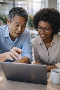Two professionals collaborating on a project using a laptop