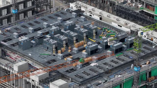 Construction crane moving hvac units on rooftop