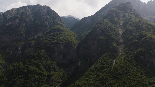 Aerial view of majestic mountains covered in lush green vegetation, creating a striking contrast against the rocky terrain, Teth, Shkoder County, Albania.