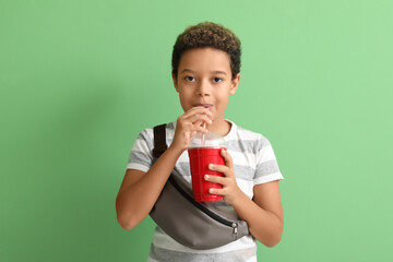 Little African-American boy with cup of cola on green background © Pixel-Shot