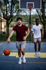 Naklejka premium Male athlete dribbling basketball on outdoor court