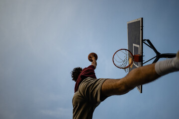 Athlete dunking basketball against a clear blue sky © Zoran Jesic