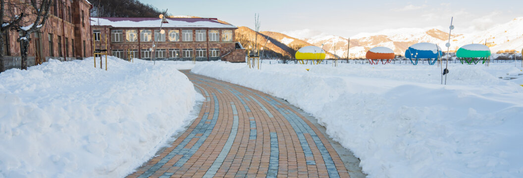 Winter road surrounded by high snow banks on both sides, scenic cold landscape showing transportation route through snowy countryside.