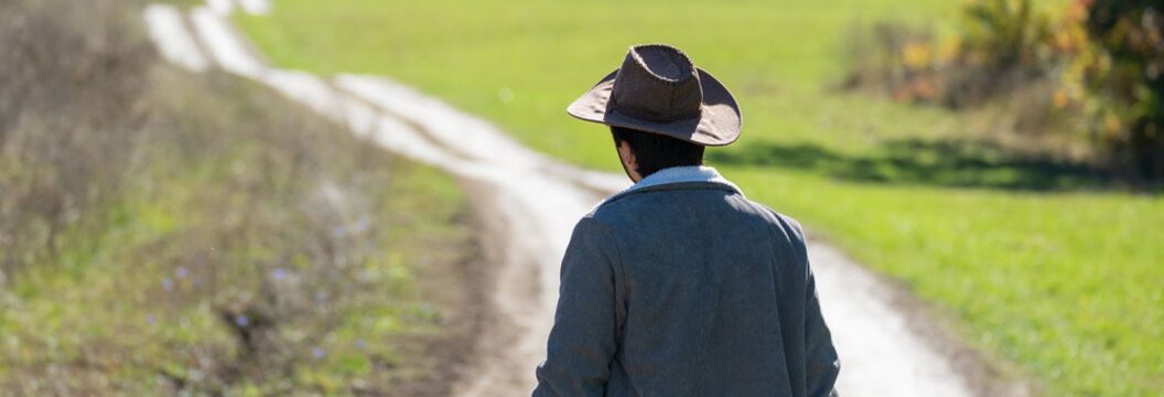 Man standing at the edge of a valley road, observing the scenic landscape ahead, reflecting contemplation, adventure, and connection with nature.