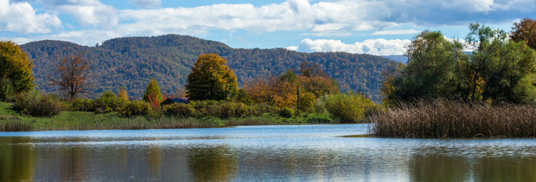 Calm lake surrounded by green hills and forest, beautiful natural scenery reflecting peaceful outdoor environment and fresh summer landscape.