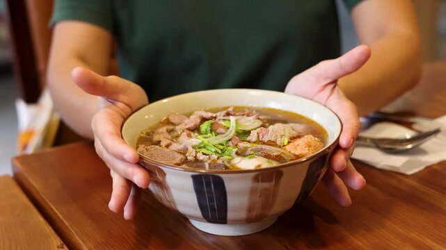 Asian Person Presenting a Large Bowl of Vietnamese Bun Cha Noodle Soup
