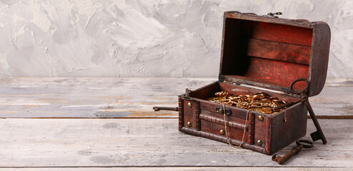 Old chest with treasures and keys on light wooden table near grunge wall © Pixel-Shot