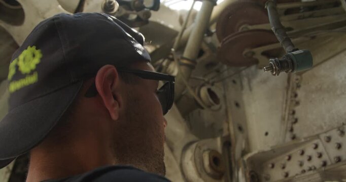 Close up of a person using a hammer and tool to work on the internal mechanical parts of an aircraft