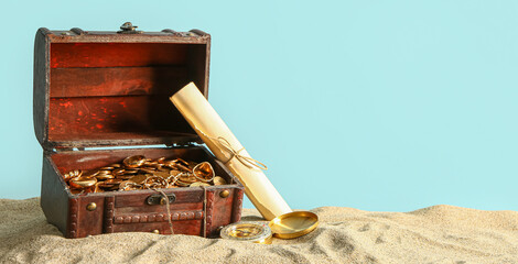 Old chest with treasures , map and compass on sand against blue background © Pixel-Shot