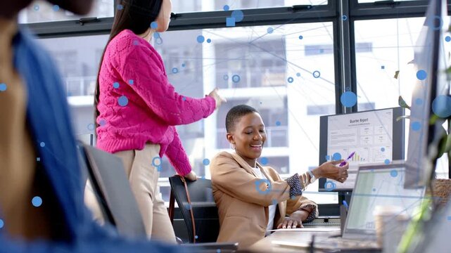 Seated woman pointing pen at monitor peer coming and working animated blue net marking data chart
