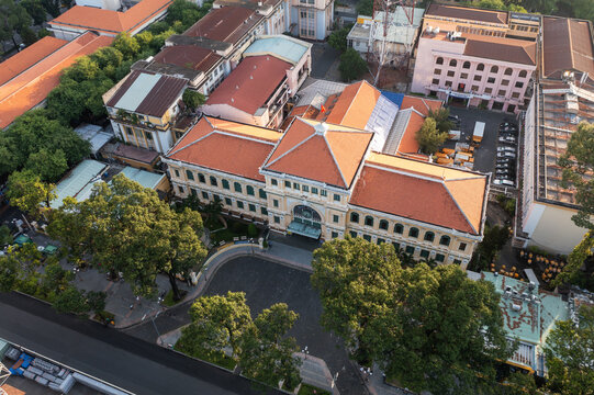 Aerial view of the Saigon Central Post Office, a French colonial masterpiece, stands amidst lush greenery and urban architecture, Ho Chi Minh City, Vietnam.