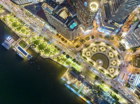 Aerial view of the illuminated Bach Dang Park and the roundabout near the Saigon River, with the city's skyline ablaze with light, Ho Chi Minh City, Vietnam.