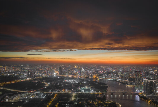 Aerial view of the Chao Phraya River winding through a cityscape bathed in the warm glow of twilight, Bangkok, Thailand.