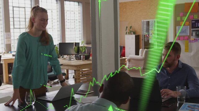 Presenter starting at open office table, leaning and gesturing, driving green finance graph upward