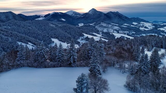 Aerial hyperlapse of dramatic clouds moving over winter mountain peaks and snowy forest