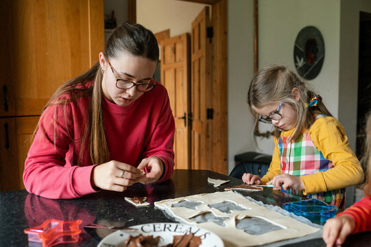 Teenager baking with her little sister baking with puff pastry and chocolate spread and concentrating