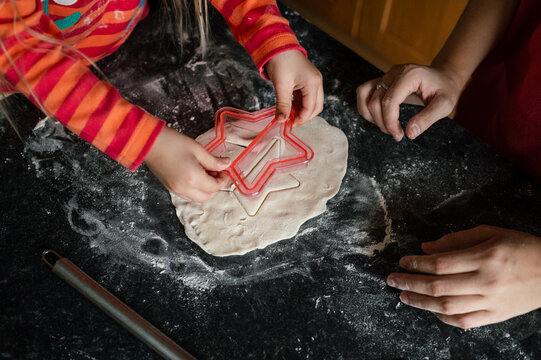 Hands of child and teenage sister using a star shaped cookie cutter on pastry