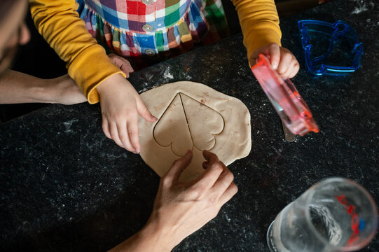 Hands of child and mother using a heart shaped cookie cutter on pastry