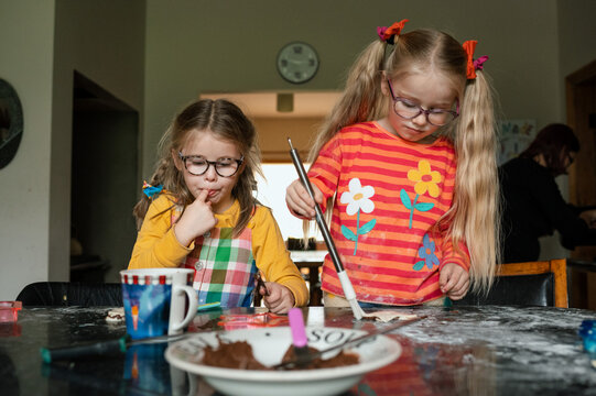 Sisters enjoying baking in their kitchen and tasting yummy chocolate spread