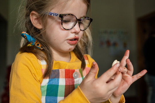 Child with chocolate spread face rolling pastry in her hands