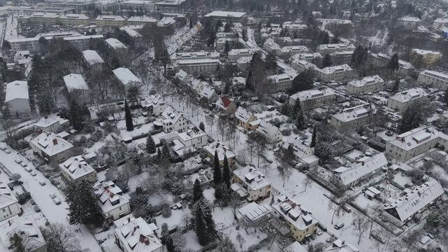A cinematic drone orbit around a quiet, snow-covered residential district in Berlin, Germany.