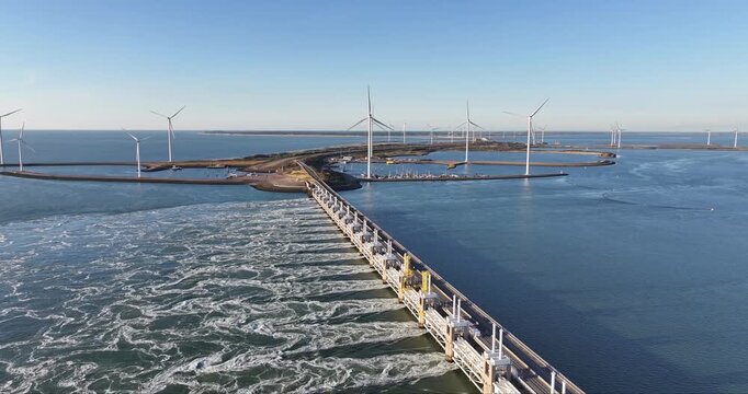 Aerial view of the Oosterscheldekering barrier, a marvel of engineering amidst swirling waters and distant wind turbines, Veersedam, Netherlands.
