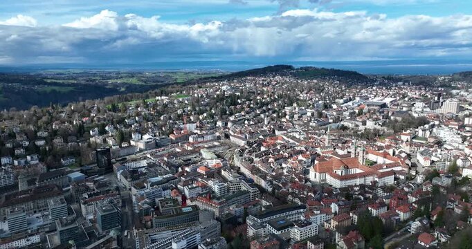 Aerial view of St. Gallen reveals terracotta rooftops contrasting against the verdant hills under a cloudy sky, St. Gallen, St. Gallen, Switzerland.