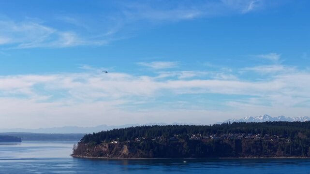 Helicopter fast flying over ocean with mts and island in background