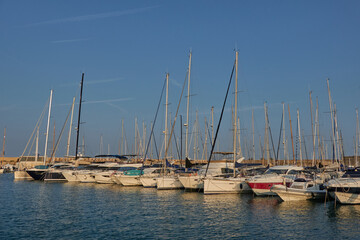 Obraz premium Antibes, France - June 8, 2025 - Many sailboats docked in a harbor under a clear blue sky with contrails
