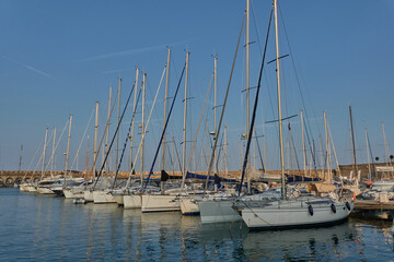 Obraz premium Antibes, France - June 8, 2025 - Many sailboats docked in a harbor under a clear blue sky with contrails