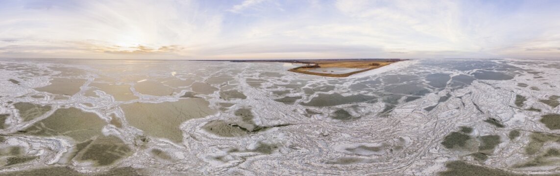 Aerial view of a mosaic of ice floes and ice shove on frozen waters of lake Markermeer in winter along the coast of Noord-Holland with nature reserve De Neck, in 360 degrees panorama, Netherlands.