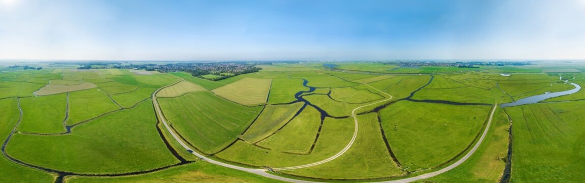 Aerial view of a patchwork of old grassland plots with ditches and roads in meadow bird reserve, in 360 degrees panorama in front of village Limmen, Het Oosterveld, Noord-Holland, Netherlands.