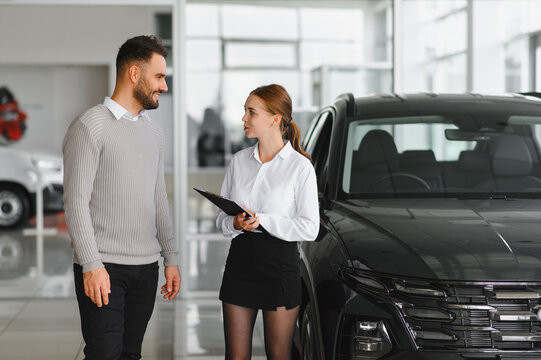 Car saleswoman consulting male customer about new vehicle