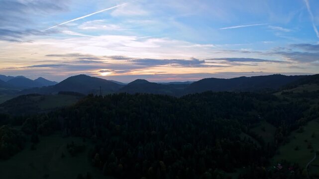 Panoramic view of moody twilight over forested hills and cloudy sky