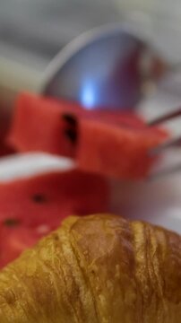 Croissant watermelon fork table with breakfast served, a knife, spoon and fork of bronze color with elegant black stand out