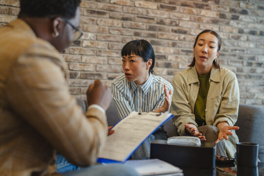 Counselor mediating discussion between two women during conflict resolution session