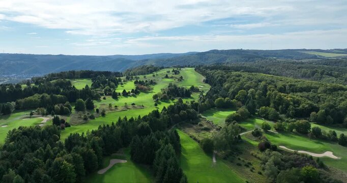 Aerial view of the Golfclub Jakobsberg, a golf course with lush green grass and trees, nestled in a hilly landscape, Marksburg Braubach, Germany.