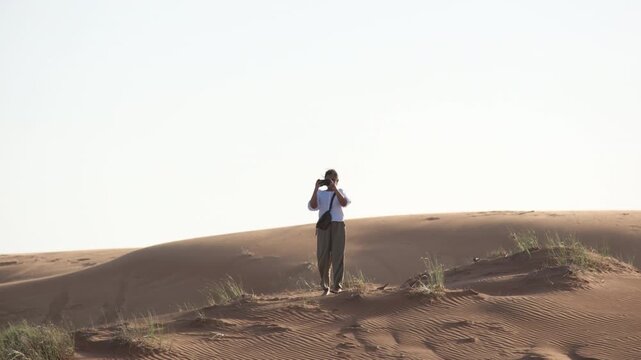 Solo female traveler taking photos in desert, hiking, and dunes, camping in desert