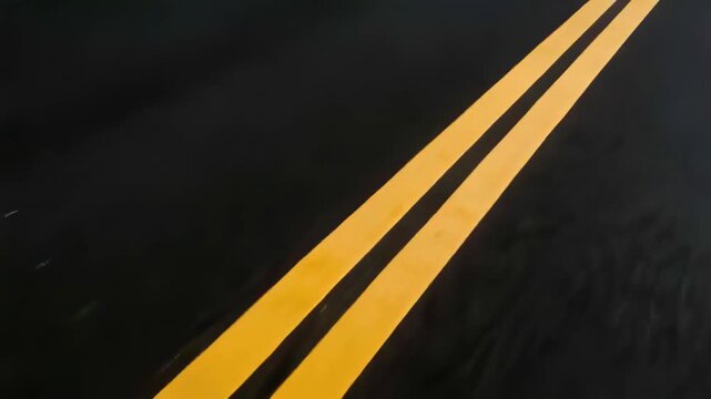 Tracking double yellow centerlines sliding on asphalt at right, handheld camera recording scuffs