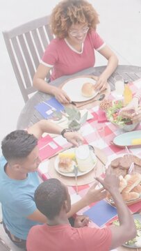 Vertical video: Arm reaching salad bowl, three friends serving bread, pouring drinks preparing food