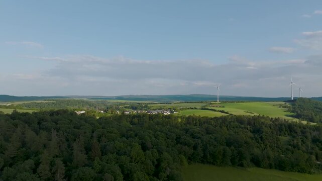 Aerial view of green fields and a village, alongside wind turbines contrasting against the sky, creating a vibrant landscape, Neuwied, Rhineland-Palatinate, Germany.