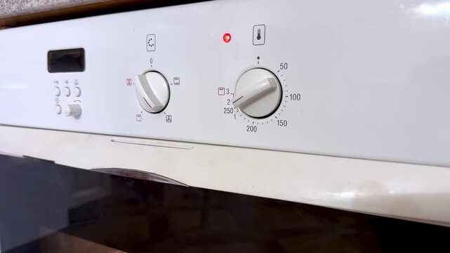 Close Up White Oven Control Panel Knob Turning To Preheat Red Indicator Light Glowing Numeric Temperature Dial