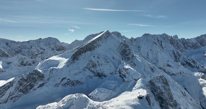 Aerial view of snow dusted mountain peaks with jagged ridges and sunlit slopes, set against a clear blue sky, Garmisch-Partenkirchen, Bavaria, Germany.