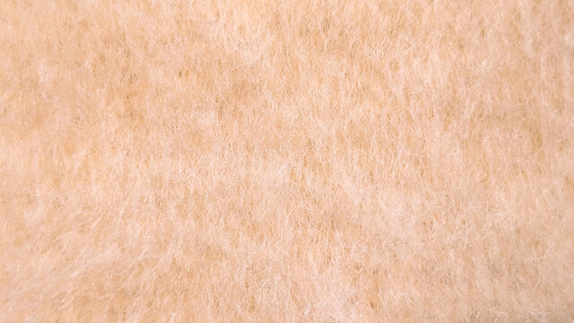 Macro texture of soft fluffy peach-colored wool fleece