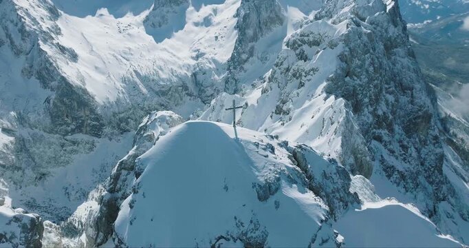 Aerial view of the stark white, snow-covered peak of Zugspitze and the deep blue Eibsee contrasting with the surrounding snow-dusted forests, Garmisch-Partenkirchen, Bavaria, Germany.