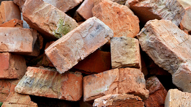 old brick. red brick. a haphazardly thrown pile of old broken bricks. a concept of a ruin, a war or natural disaster, construction, renovation. building materials, dismantling. for background. closeup