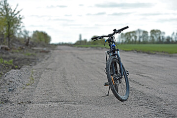 Fototapeta premium Mountain bike. stands on a field road. spring or autumn. concept of cycling, repair or breakage, sports, outdoor activities. bike on trail, front wheel in focus. healthy lifestyle