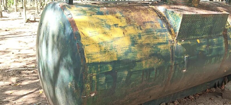 Weathered industrial metal tank in a rural setting, exhibiting severe rust and peeling paint, a symbol of abandoned utility and environmental decay